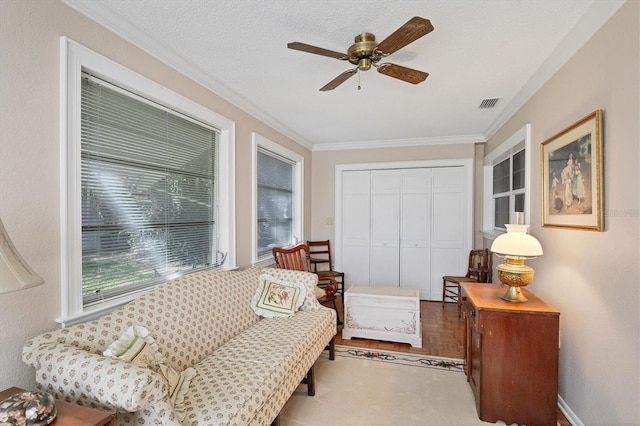 sitting room with ceiling fan, a textured ceiling, and ornamental molding