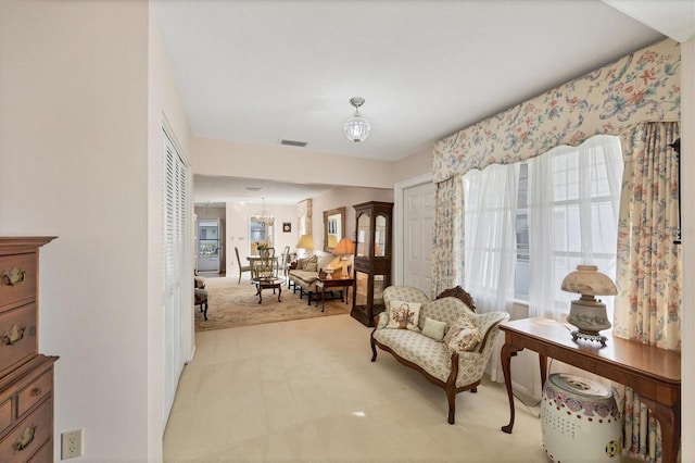 living area featuring light colored carpet and a notable chandelier