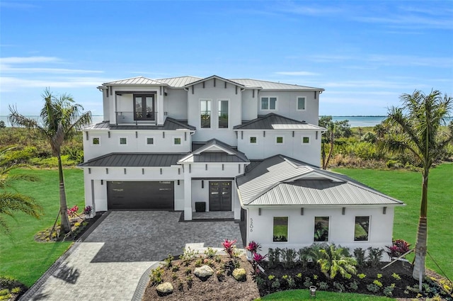 view of front of house with a front lawn, a garage, and a water view