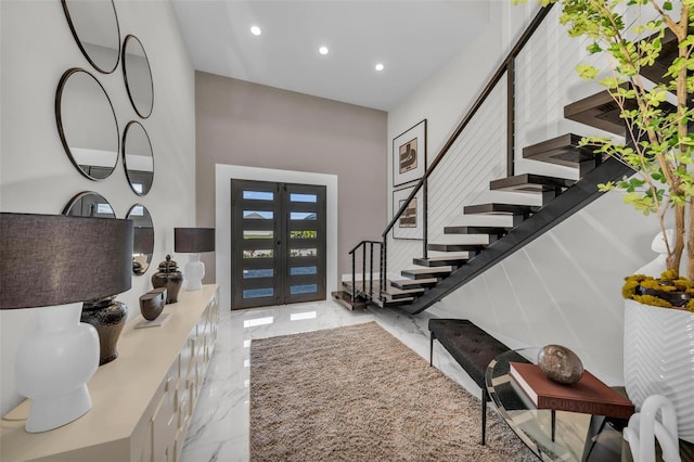 entryway with a towering ceiling, french doors, and light tile flooring