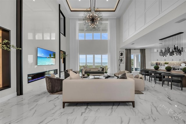 living room with a tray ceiling, light tile flooring, a chandelier, and a high ceiling