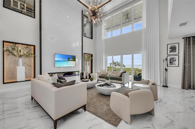 living room featuring light tile flooring, a notable chandelier, and a high ceiling