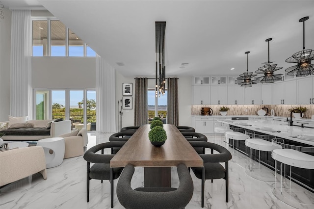 dining space with a notable chandelier, light tile floors, and a towering ceiling