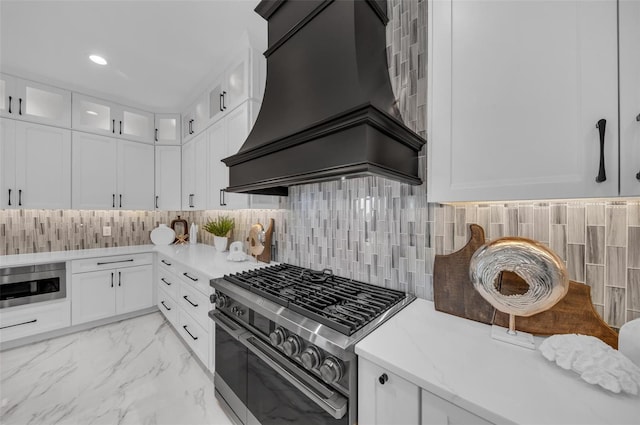 kitchen featuring white cabinets, backsplash, custom range hood, and stainless steel appliances