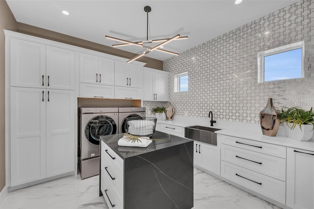 kitchen with tasteful backsplash, washer and clothes dryer, white cabinets, and sink