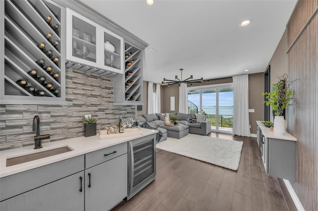 kitchen featuring wine cooler, gray cabinets, dark wood-type flooring, backsplash, and sink