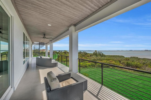 balcony with a water view, an outdoor living space, and ceiling fan