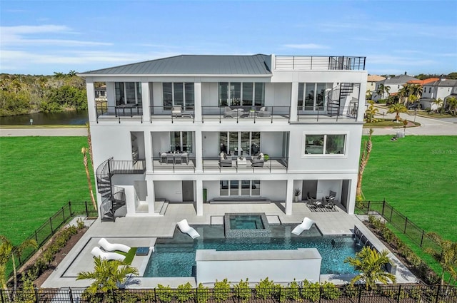 rear view of house featuring a pool with hot tub, a balcony, a patio area, and a lawn