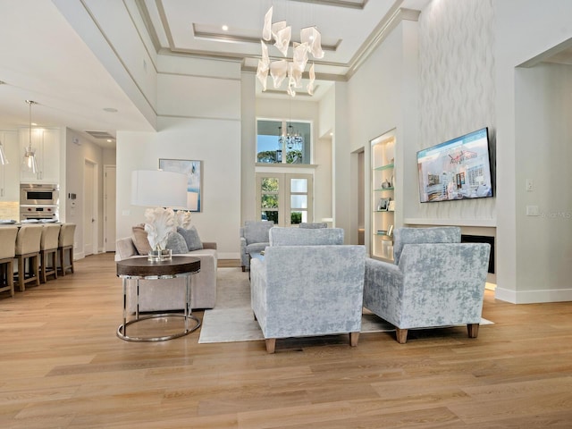 living room featuring light hardwood / wood-style floors, a notable chandelier, french doors, a towering ceiling, and a raised ceiling