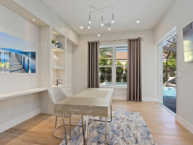 dining area featuring a chandelier, built in shelves, and light wood-type flooring