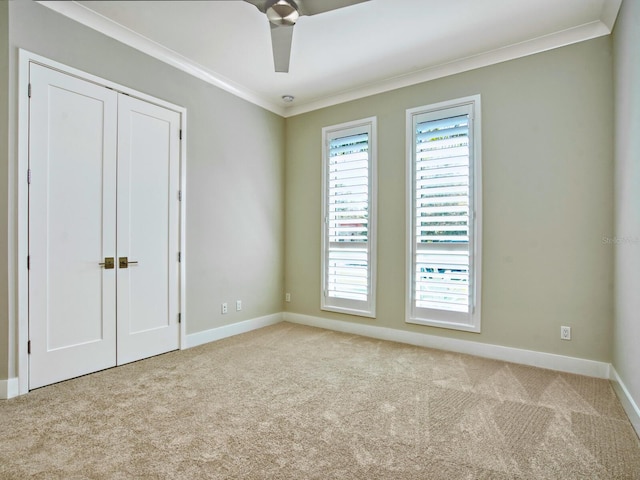 unfurnished room with ornamental molding, ceiling fan, and light colored carpet