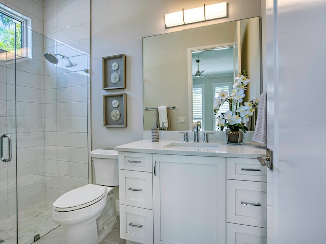 bathroom with toilet, a shower with shower door, ceiling fan, vanity, and tile flooring