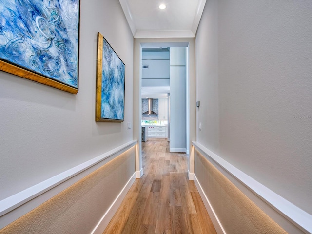 hallway with ornamental molding and light hardwood / wood-style flooring