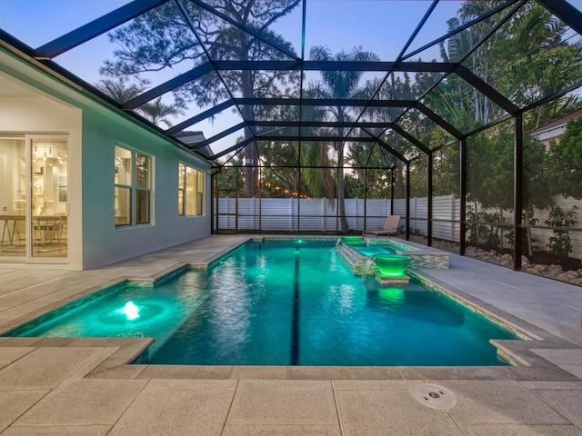 pool at dusk featuring a lanai, a jacuzzi, and a patio area