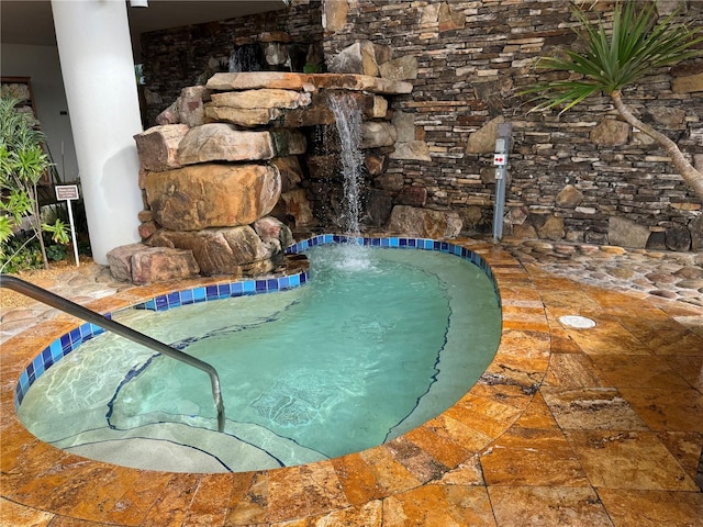 view of pool featuring an in ground hot tub and pool water feature