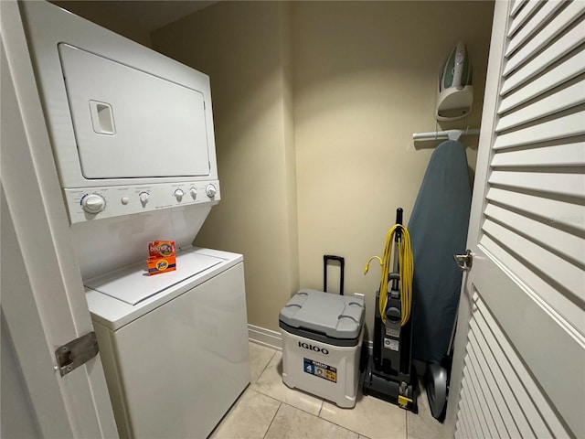 clothes washing area with stacked washing maching and dryer and light tile floors