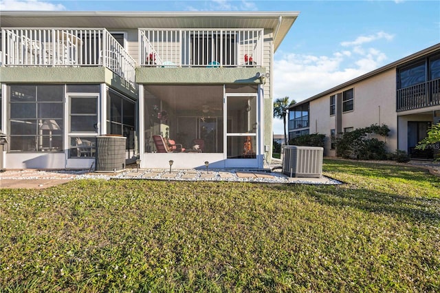 back of property with a lawn, a balcony, a sunroom, and central air condition unit