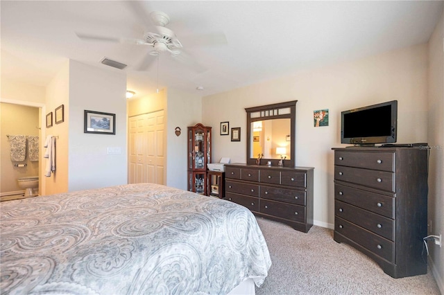 bedroom featuring ceiling fan, a closet, light carpet, and ensuite bathroom