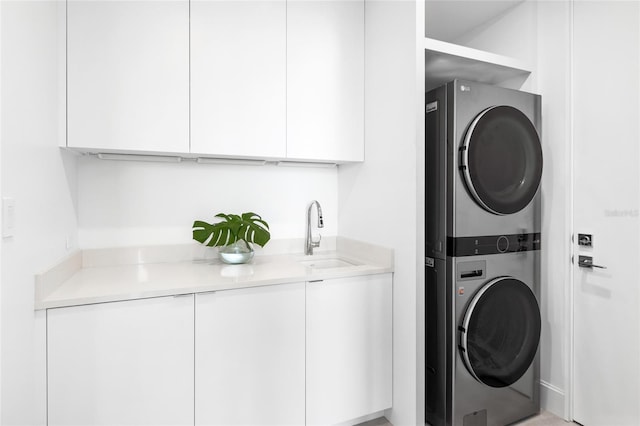 washroom featuring stacked washer / dryer, sink, and cabinets