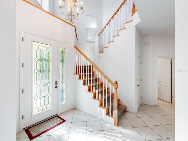 entrance foyer with light tile floors, a towering ceiling, and an inviting chandelier