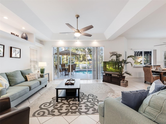 tiled living room featuring a raised ceiling and ceiling fan