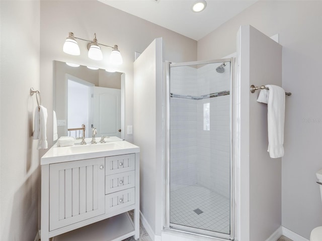 bathroom featuring a shower with door, vanity with extensive cabinet space, and toilet