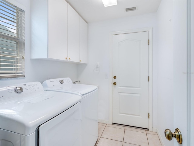 laundry area with washing machine and dryer, light tile floors, and cabinets