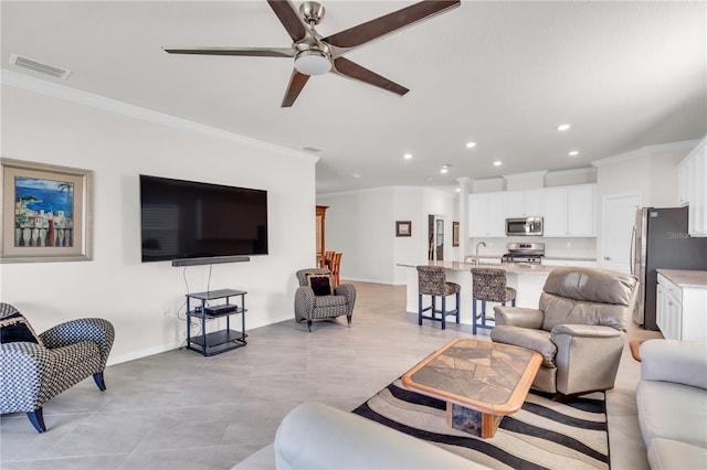 tiled living room featuring ceiling fan, sink, and ornamental molding