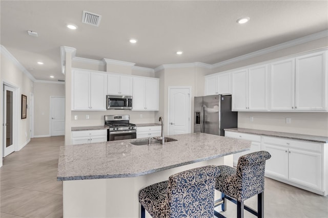 kitchen with white cabinets, stainless steel appliances, sink, and an island with sink