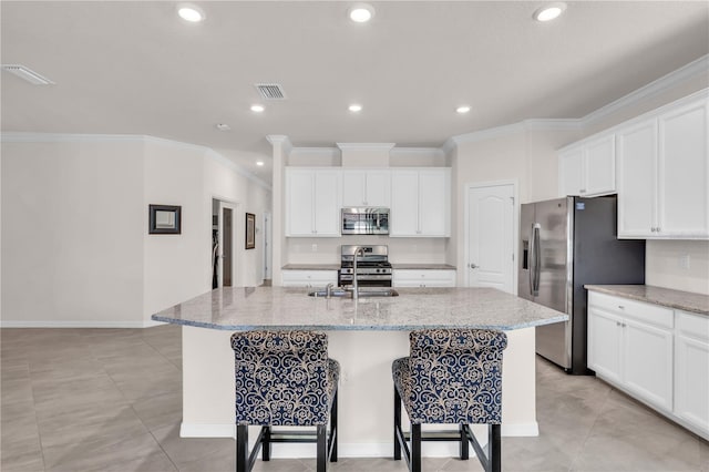 kitchen with light stone countertops, crown molding, a center island with sink, and stainless steel appliances