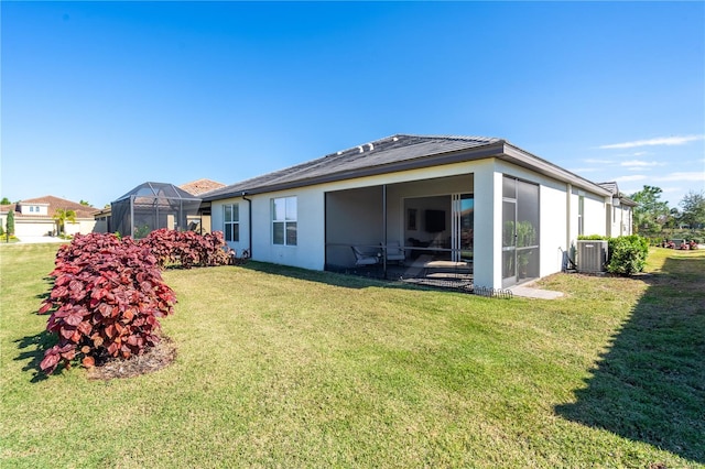 rear view of property with a lawn, a lanai, and central AC