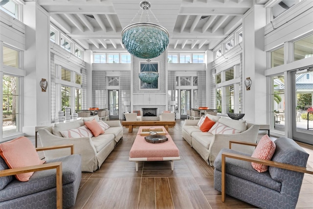 sunroom / solarium featuring a chandelier, beamed ceiling, a wealth of natural light, and a large fireplace