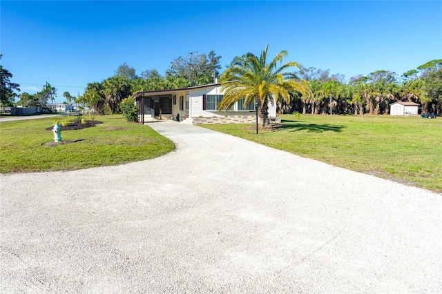 view of front facade with a storage unit, a carport, and a front lawn