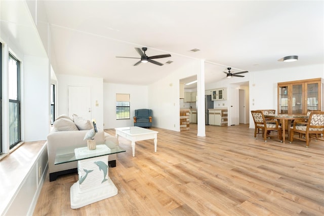 living room featuring ceiling fan, vaulted ceiling, and light hardwood / wood-style flooring