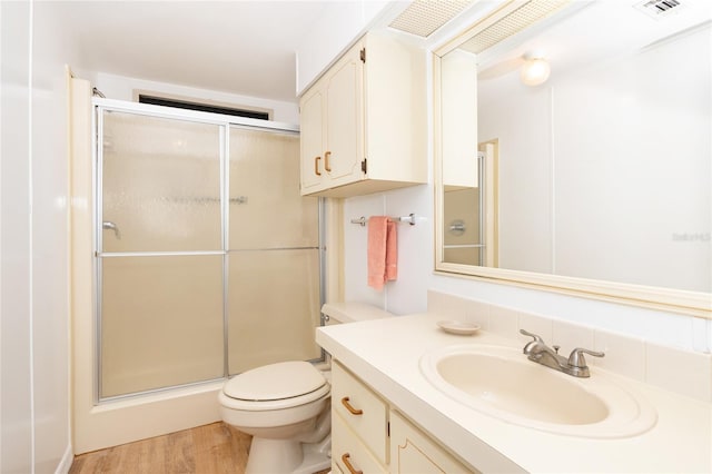 bathroom with toilet, hardwood / wood-style floors, a shower with shower door, and oversized vanity