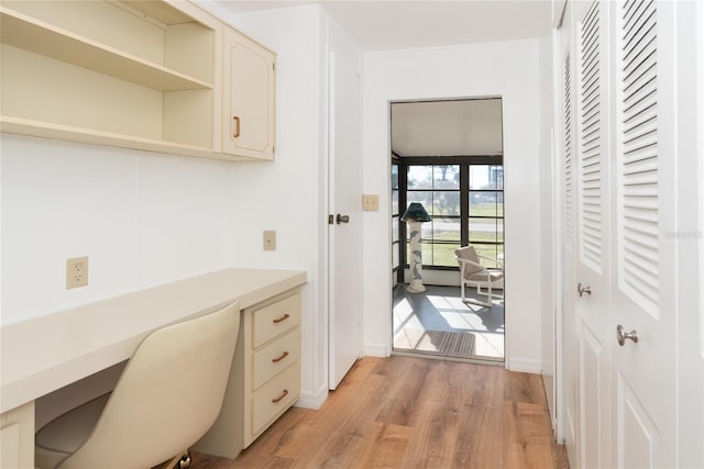 office space with built in desk and light hardwood / wood-style flooring