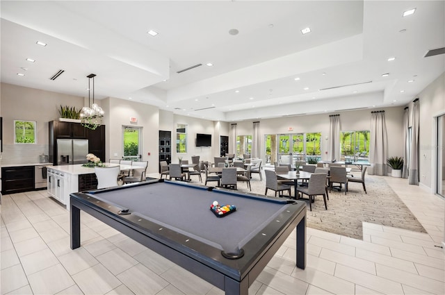 recreation room featuring a tray ceiling, light tile floors, a notable chandelier, and pool table