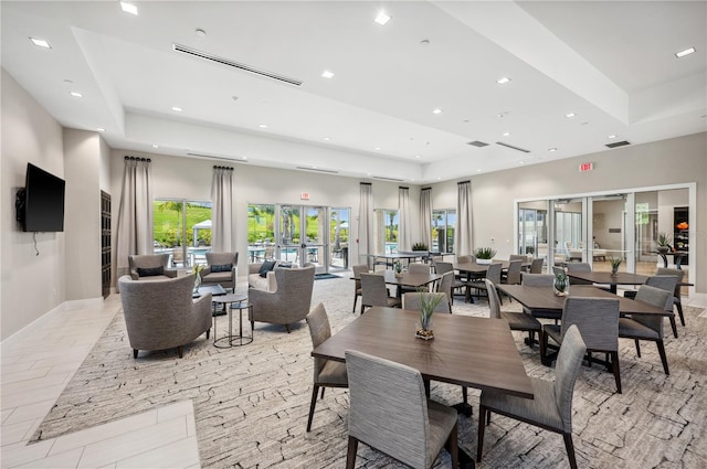 tiled dining space featuring french doors and a raised ceiling