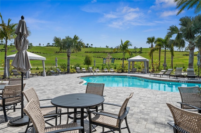 view of pool with a yard, a gazebo, a rural view, and a patio