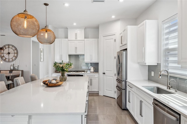 kitchen featuring white cabinetry, backsplash, sink, stainless steel appliances, and pendant lighting