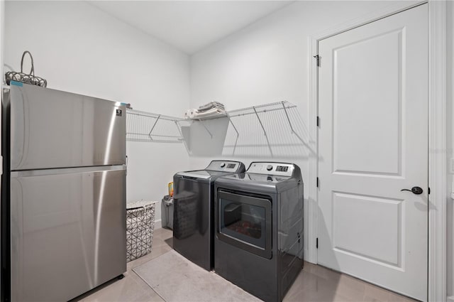 clothes washing area featuring separate washer and dryer and light tile floors