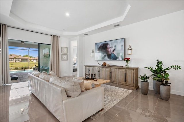 living room featuring a raised ceiling, visible vents, and baseboards