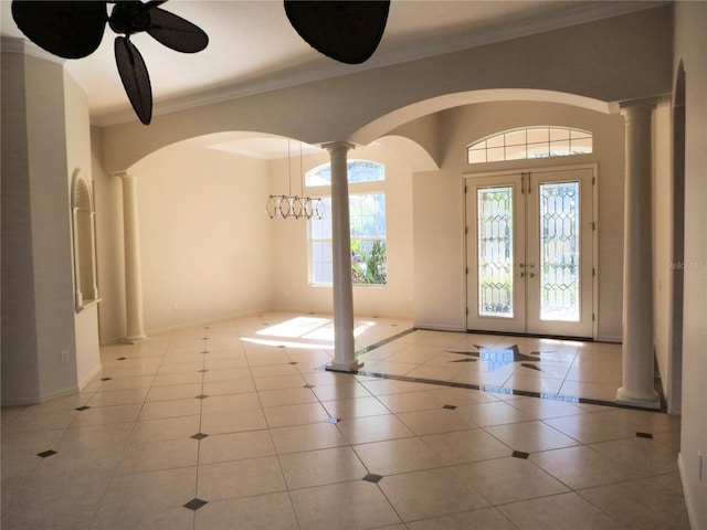 tiled entryway with ornamental molding, decorative columns, and plenty of natural light