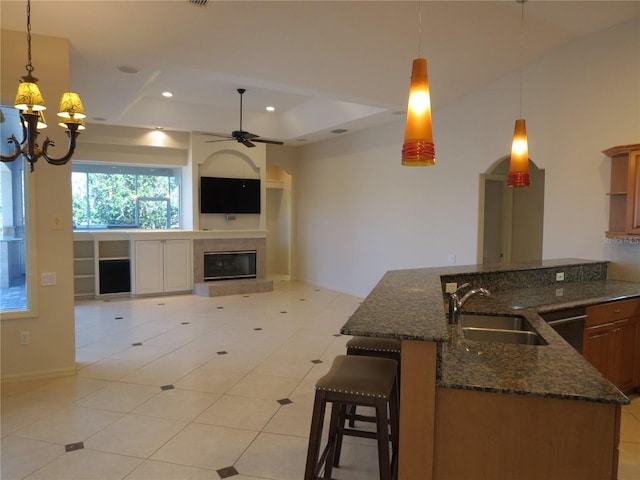 kitchen featuring pendant lighting, sink, a kitchen breakfast bar, dark stone counters, and light tile patterned floors