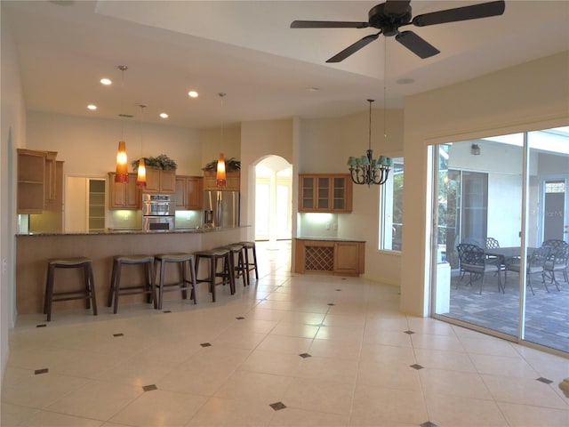 kitchen featuring appliances with stainless steel finishes, a breakfast bar, ceiling fan with notable chandelier, light tile patterned floors, and kitchen peninsula