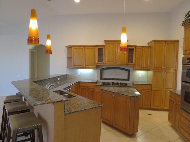 kitchen featuring a kitchen bar, decorative light fixtures, kitchen peninsula, and decorative backsplash