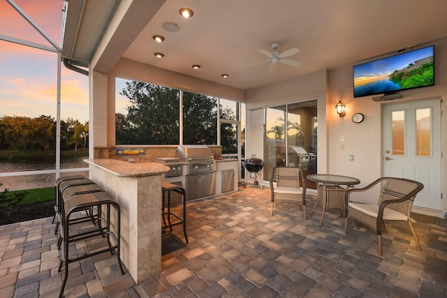 view of patio featuring ceiling fan, area for grilling, and exterior bar