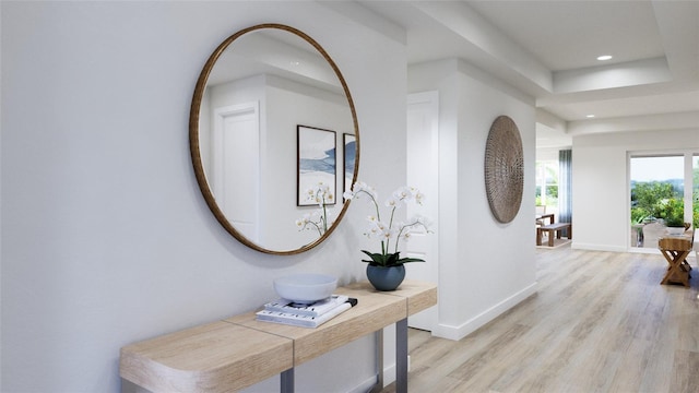 hall with a raised ceiling and light hardwood / wood-style flooring