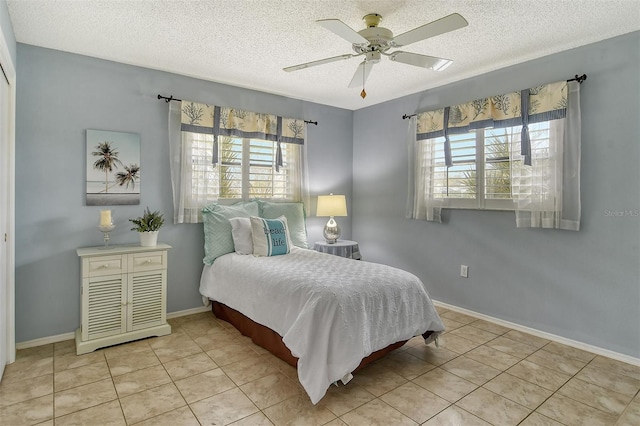 bedroom featuring ceiling fan, light tile patterned flooring, and a textured ceiling