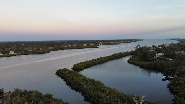 aerial view at dusk featuring a water view